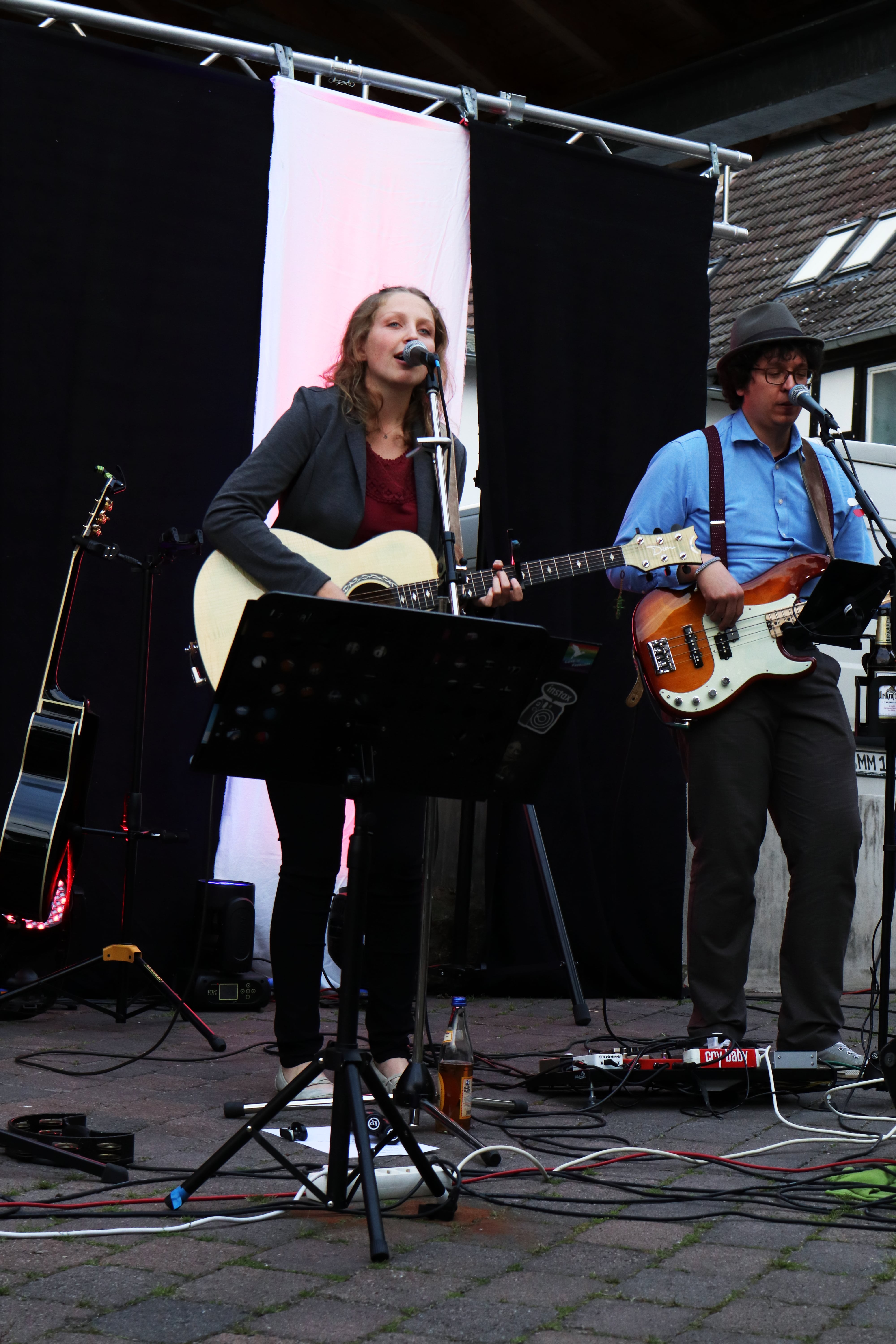 Auf dem Bild sieht man Charlotte, wie sie Gitarre spielt und singt. Rechts neben ihr steht Chritoph, welcher Bass spielt.
